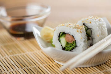Zwei modern Style Inside Out Sushi mit Lachs, Rucola und Gurke mit Sojasoße und Holz Stäbchen