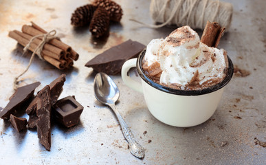 Cup of hot chocolate cocoa with whipped cream and dark chocolate  slices on vintage metale background. Delicious cold weather beverage concept.