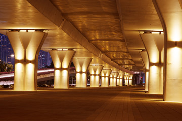 empty sidewalk below elevated road in modern city