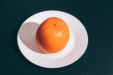 Orange persimmon on a white plate