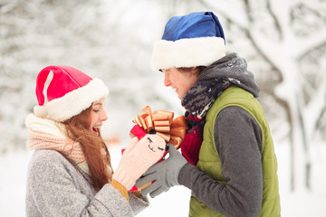 An attractive lady in a funny hat takes a present. She definetely likes it.