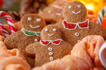 Cookies in the form of little people close-up and lollipops on the background of a glowing garland. Family celebrating the new year.