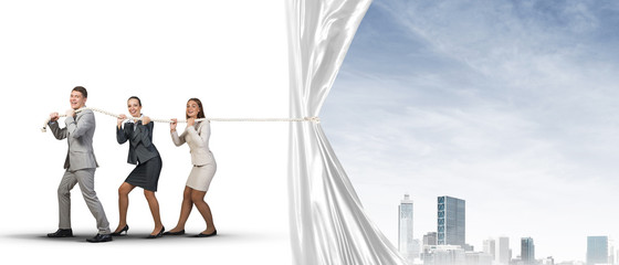 Young businesspeople working in collaboration and pulling white advertisement banner