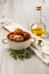 Fried meat cutlets in ceramic soup bowl, branch of fresh parsley, bottle with sunflower oil and kitchen towel with spoon