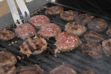 Fresh meatballs grilled outdoors on a gas grill. Meatballs on a barbecue
