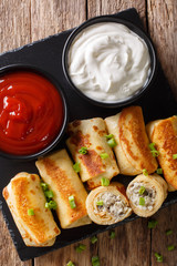 Pancakes rolls with chicken, cheese and mushrooms close-up and sauces. Vertical top view
