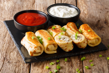 Delicious crepes rolls with chicken, cheese and mushrooms close-up and sauces. horizontal