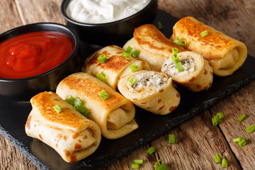 Pancakes rolls stuffed with chicken and mushrooms close-up and tomato sauce, sour cream. horizontal
