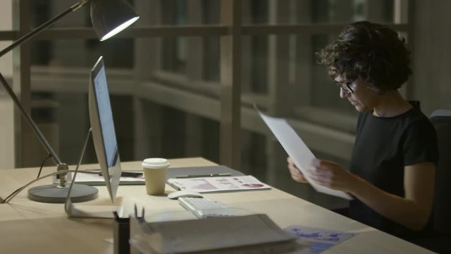 Businesswoman typing on computer and writing on document in the office at night