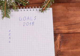 Christmas decorations, spruce branches and a notebook with tasks. wooden background