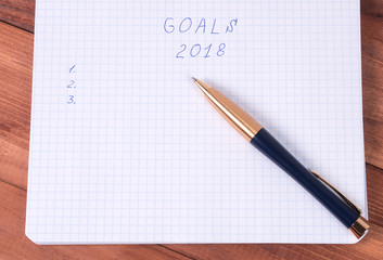 notebook with plans for the new year and pen on a wooden background