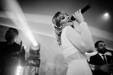 Musicial music live band performing on a stage with different lights. Beautiful blonde vocal singer...