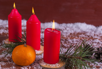 Winter decoration with mandarins and burning candles and fir branches