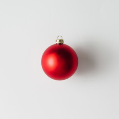 Minimal red Christmas bauble on bright background. Flat lay. HOliday concept.