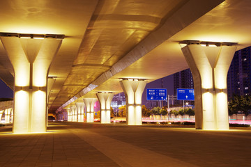 empty sidewalk below elevated road in modern city