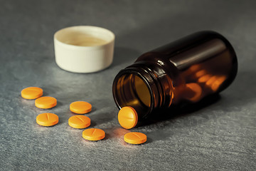 A pills and dark glass bottle on gray background with copy space. Focus on foreground.