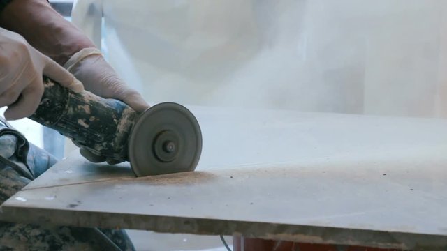 Worker cutting a tile using an angle grinder at construction site