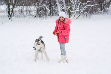 Little girl walking with a Siberian husky breed dog in the winter in the snow