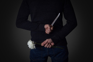 Man Holds the Knife and the Flower behind His Back. The Concept of the Danger of Visiting Blind