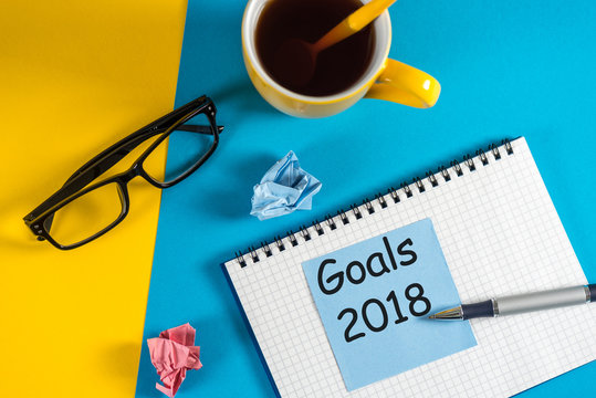 Goals 2018. Life and business goal, plan and resolutions concept for new year concept. Note at blue and yellow background with morning coffee cup