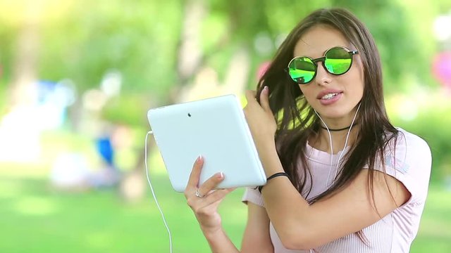 Beautiful woman communicates via tablet computer. Attractive woman with white tablet computer communicates through skype or video chat, female with tablet pc