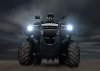 A man riding ATV in sand in protective  helmet. Against dark cloudy sky. Blur effect. © Paopano