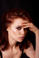 Obraz premium Girl in Studio on dark background. Red hair, great figure. Mysterious, arms crossed around the lips. The pensive look