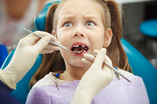 Scared child sits at dentist chair with open mouth - Powered by Adobe