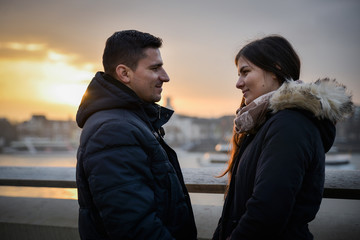 Romantic couple sitting on a bridge at sunset