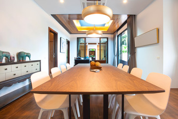 Luxury interior design in living room of pool villas. Airy and bright space with high raised ceiling and wooden dining table