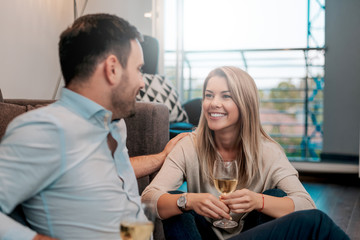 Cheerful couple sitting on floor and talking while looking at each other.