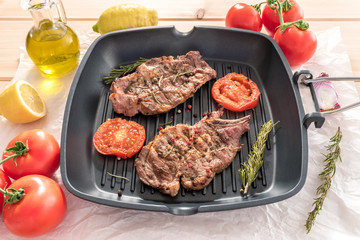 Grilled steak on grill pan with tomatoes on wooden background