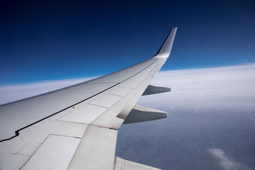 Fototapeta na wymiar Plane wing flying above the clouds 