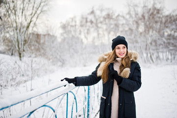 Fototapeta na wymiar Beautiful brunette girl in winter warm clothing. Model on winter jacket and black hat.