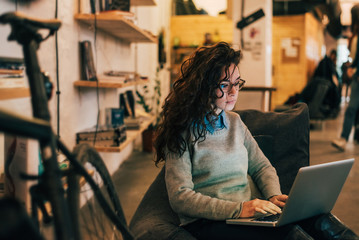 Woman with glasses using laptop in modern interior.