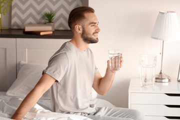 Morning of handsome young man drinking water at home