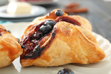 Tasty puff pastry with blueberries on plate, closeup