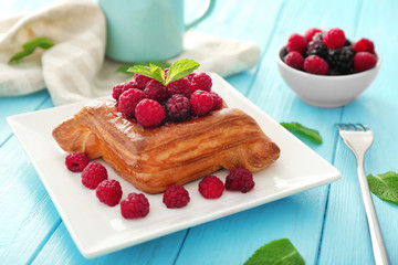 Plate with raspberry pastry on wooden table