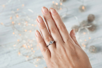 Woman wearing luxury engagement ring on light background, closeup