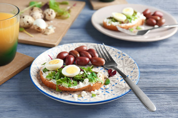 Plate with toast, cheese and quail egg on table
