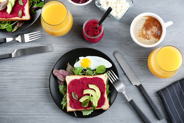Fototapeta na wymiar Plate with toast, beet paste and avocado on wooden table