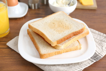 Plate with tasty crispy toasts on wooden table