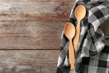 Clean kitchen towel and spoons on wooden table, top view
