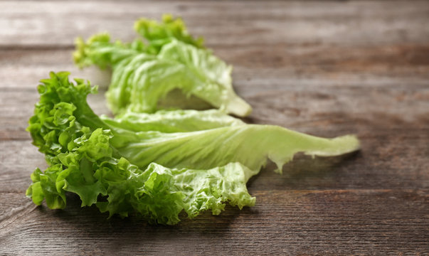 Leaves of fresh green salad on wooden table