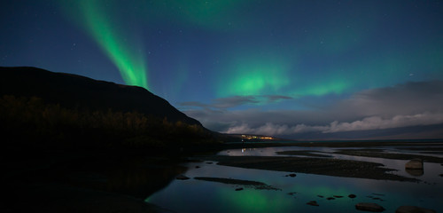 Fototapeta na wymiar Northern lights dancing over calm lake in Abisko national park in Sweden