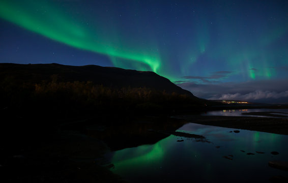 Northern lights dancing over calm lake in Abisko national park in Sweden