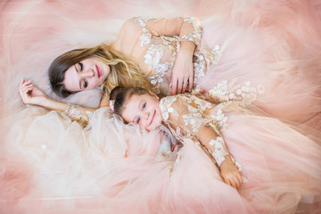 Creative portrait of a beautiful mother and daughter, fashion, in a gorgeous long dress