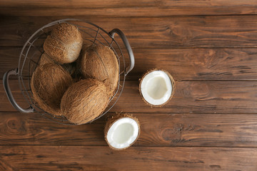Metal basket with coconuts on wooden background