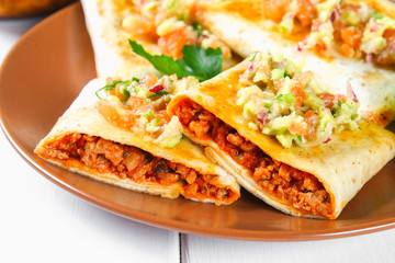 Traditional Mexican dish - chimichanga. Corn cake with minced meat, pepper, onion, garlic, oregano, zira and guacomole sauce from avocado.