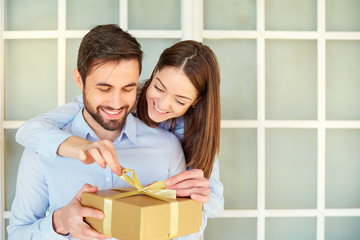The guy gives a gift box to his girlfriend. Young couple on holiday. St. Valentine's Day.